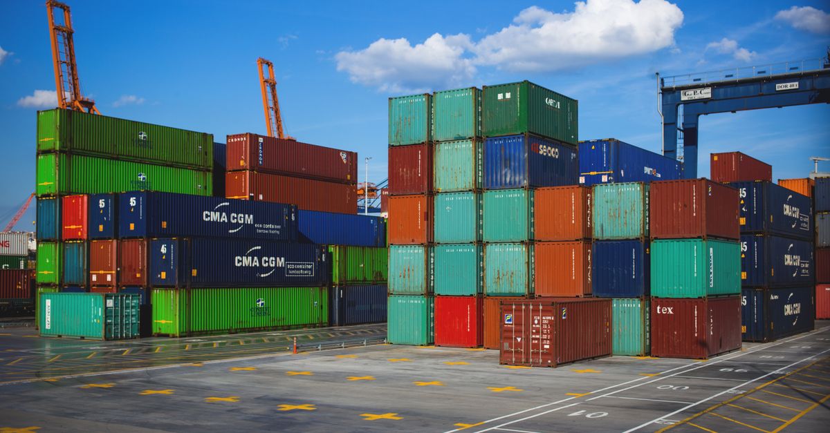 Vibrant shipping containers stacked at an industrial port under a blue sky.